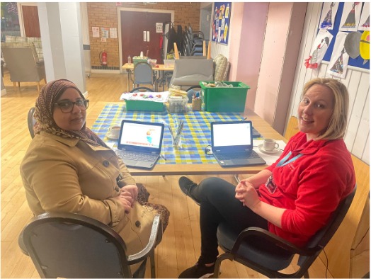 Two support workers sitting together at a table talking